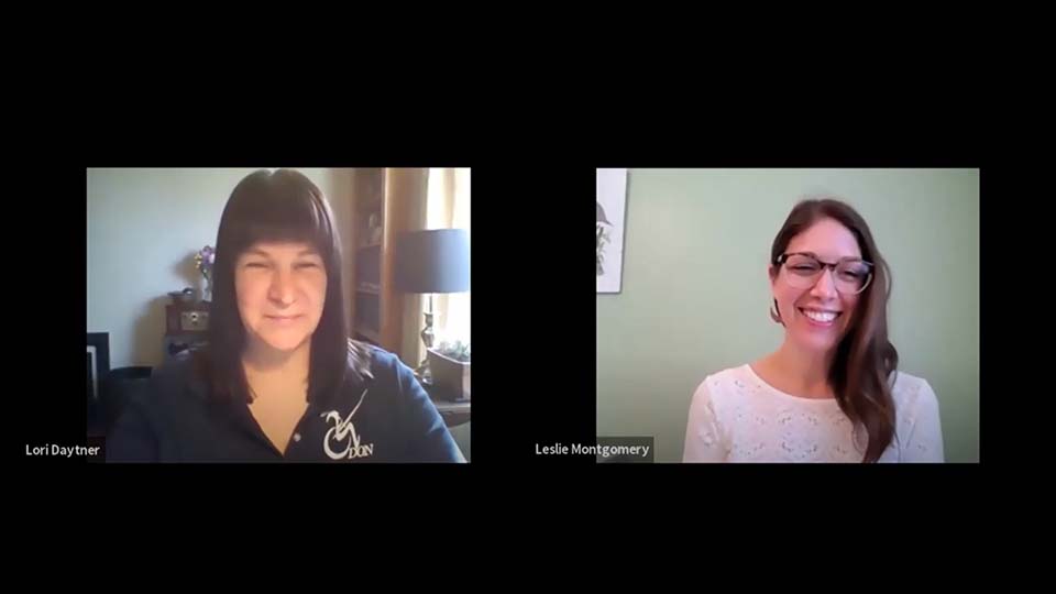 Two women are shown in a split-screen video call. On the left, a woman with dark hair smiles while wearing a dark top. On the right, a woman with light brown hair smiles, wearing a white top. Both appear engaged in conversation.